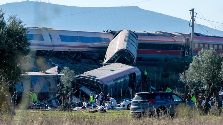 Emergency responders at the scene of a devastating train crash in Spain, with derailed cars and debris.